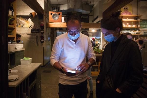 A man holds his smartphone as he presents a COVID-19 vaccination certificate before entering a restaurant in Tel Aviv on Wednesday. | GETTY IMAGES / VIA KYODO