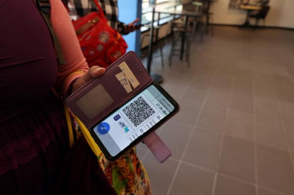 A woman shows her COVID-19 vaccination status on her mobile phone at a gym, where a 