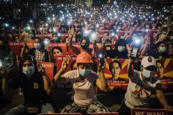 Protesters hold up the three finger salute and placards with an image of detained Myanmar civilian leader Aung San Suu Kyi while using their mobile pho<em></em>nes as lights during a demo<em></em>nstration against the military coup in Yangon, Myanmar, on Friday. | AFP-JIJI